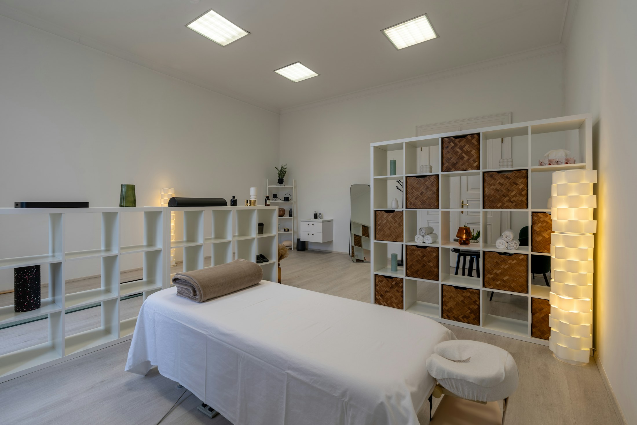 A naturally lit TATTVA GRUHAM therapy room with plants, warm lamps and a prepared treatment bed